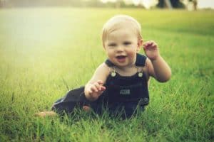 תינוק מחייך יושב על דשא